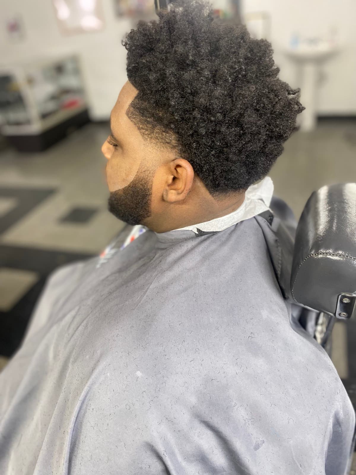 Curls on top with faded sides and beard shape-up